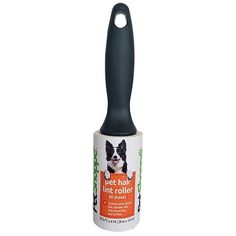 a black and white dog is sitting on the top of a bottle with a brush in it's mouth