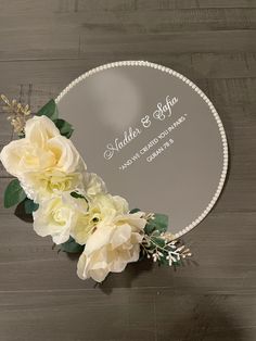 a mirror with some flowers on it and the name of the wedding day written in white