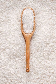 a wooden spoon filled with white rice on top of a bed of white fluffy carpet