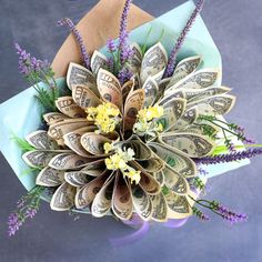 a bouquet made out of dollar bills and purple flowers on top of a blue envelope