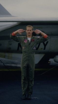 a man standing in front of an airplane with his hands on his head and arms behind his head