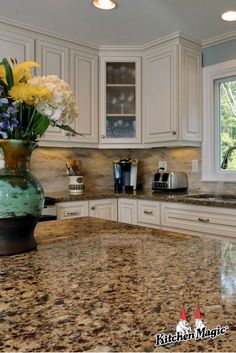 a kitchen with marble counter tops and white cabinets