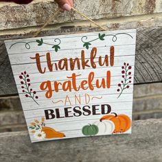 a hand holding a sign that says, thank grateful and beseld with pumpkins