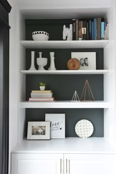 a white book shelf with books and vases sitting on it's top shelves