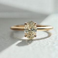 a yellow diamond ring sitting on top of a white surface with sunlight coming through the window