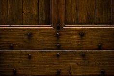 an old wooden door with knobs and nails on the bottom half, in dark wood