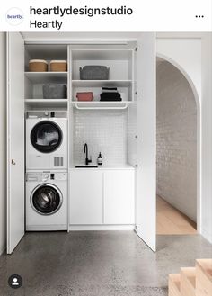 a washer and dryer in a white laundry room with open shelving on the wall