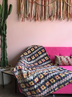 a living room with a pink couch and decorative wall hangings