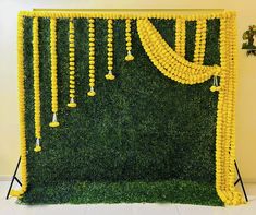 a green wall decorated with yellow flowers and beads