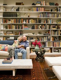 an older man and young boy sitting on a couch in front of bookshelves