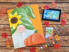 an art project is being displayed on a wooden table with autumn leaves and other arts and crafts supplies