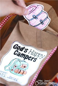 someone is holding a paper bag with some stickers on it that says god's happy campers