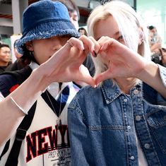 two people making the shape of a heart with their hands while standing in front of a crowd