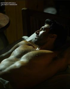 a shirtless man laying in bed with his head turned to the side and eyes closed