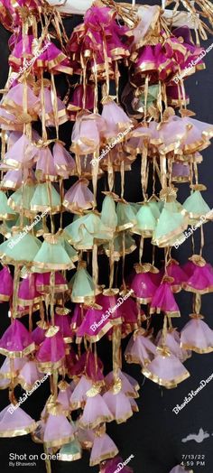 many pink and green glass chandelier hanging from the ceiling in front of a black wall