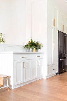 a kitchen with white cabinets and black refrigerator freezer next to a wooden flooring