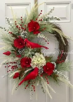 a wreath with red flowers and greenery hangs on the front door