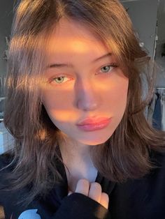 a woman with long hair and blue eyes is looking at the camera while wearing a black shirt