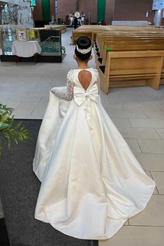 a woman in a white wedding dress is walking down the aisle with her back to the camera