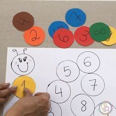 a person is holding up a piece of paper that has numbers on it and ladybugs in the background