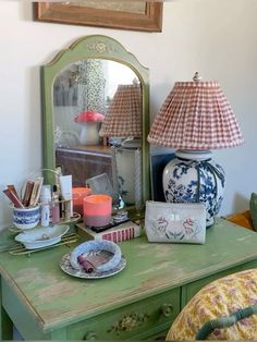 a green dresser topped with a mirror next to a lamp