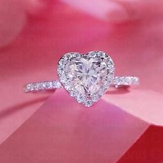 a heart shaped diamond ring on top of a pink flower