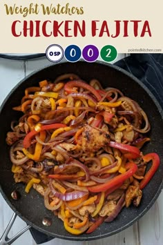 chicken fajita with peppers and onions in a skillet on a white wooden table