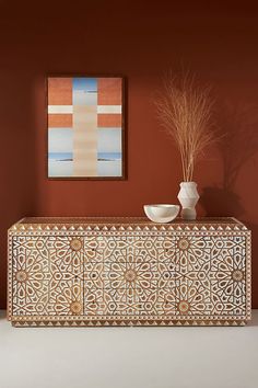 a white vase sitting on top of a wooden cabinet