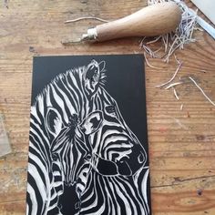 two zebras are standing next to each other on a wooden table with wire spools