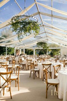 tables and chairs are set up for an event under a tent with white linens