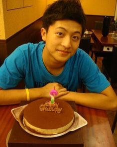 a young man sitting in front of a chocolate cake