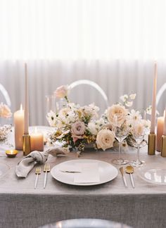 the table is set with candles, plates and silverware for an elegant wedding reception