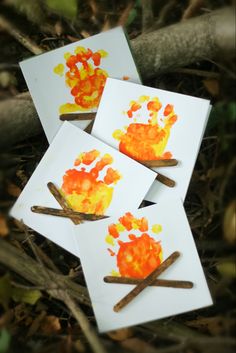 four cards with handprints on them sitting in the grass next to some sticks