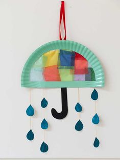 a paper plate umbrella with raindrops hanging from it's side on a wall