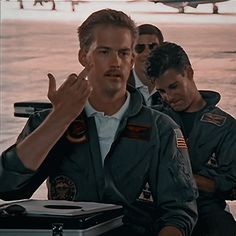 a group of men standing next to each other in front of an airplane on the water