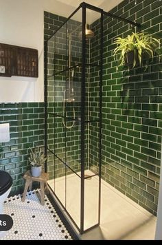 a green tiled bathroom with a black and white floor, planter on the wall