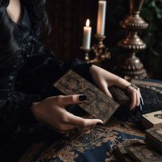 a woman sitting at a table with some cards and candles in front of her,