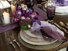 the table is set with silverware, purple flowers and napkins on top of it