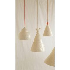 three white lamps hanging from red cords in front of a white wall with an orange cord