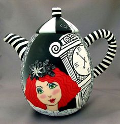 a black and white striped teapot with a red haired girl painted on it's side