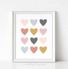 an art print with hearts in pastel colors on a white wall above a shelf