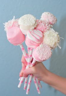 there is a person holding some pink and white lollipops in their hand