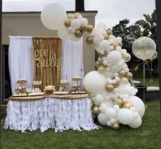 a table topped with white and gold balloons