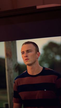 a man standing in front of a window with his head turned to the side and looking off into the distance