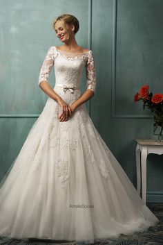 a woman in a white wedding dress standing next to a mirror and posing for the camera