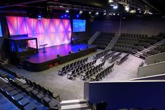 an empty auditorium with rows of chairs and a stage set up for a concert or show