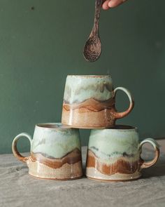 Three medium pottery mugs glazed in browns and greens to represent a coastal scene Handbuild Pottery Mugs, Hand Painting Pottery, Mug Forms Pottery, Ceramic Pottery Mugs Design, Ceramics Mugs Handmade, Glazing Mugs Ideas, Mug Throwing, Ceramic Mug Photography