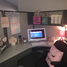 a desk with a computer, lamp and pictures on the wall in front of it