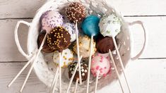 a white basket filled with cake pops covered in sprinkles and frosting