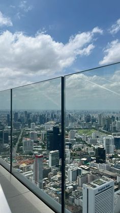 a man standing on top of a tall building next to a glass wall with cityscape in the background